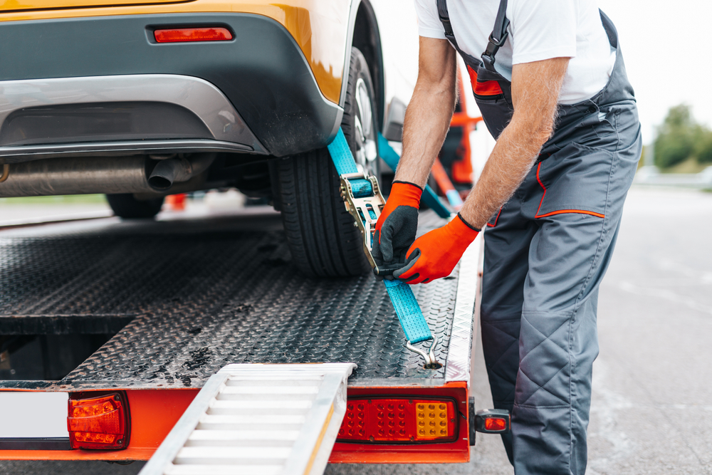 A man secures a car to a tow truck.